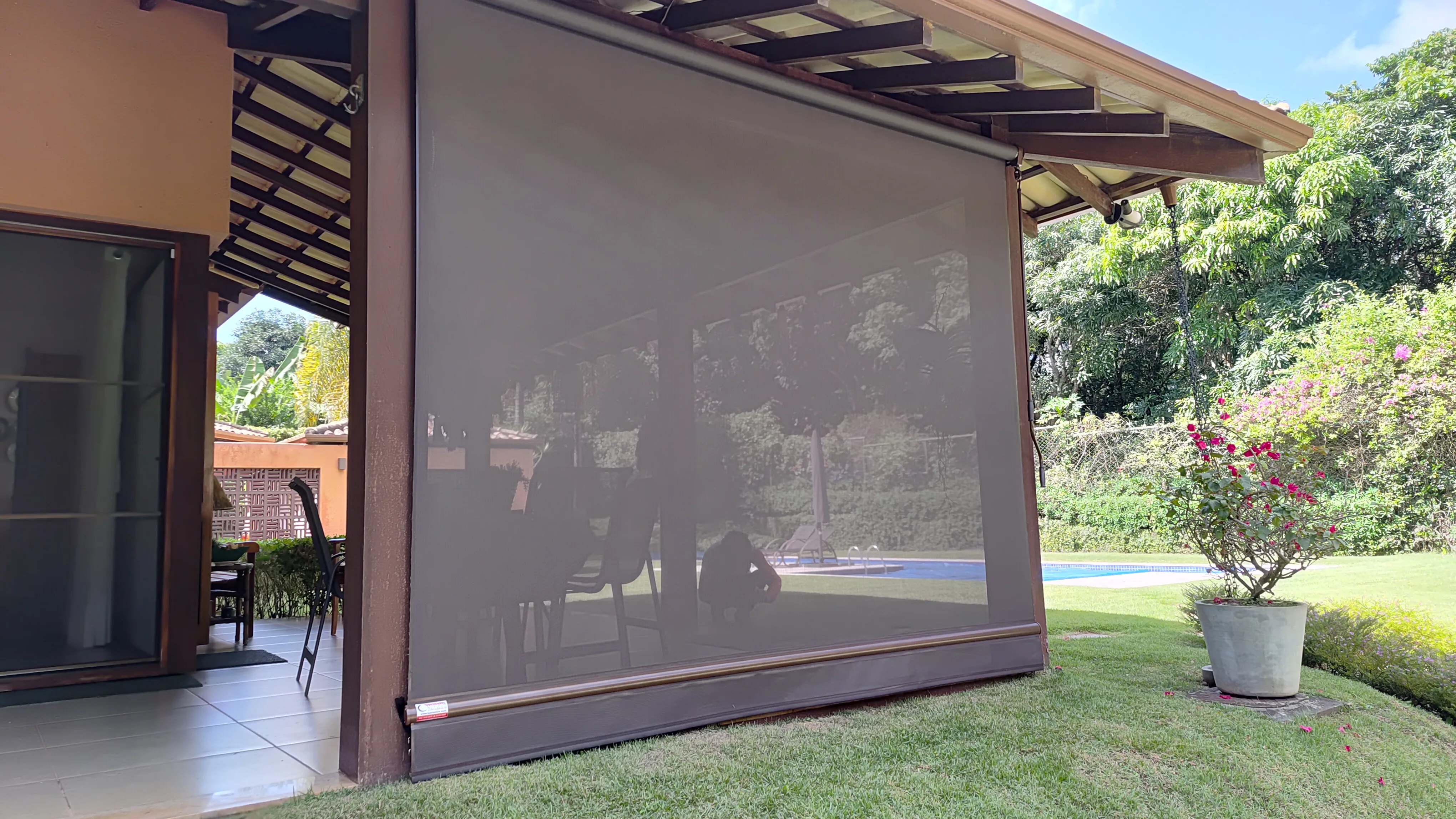 Toldo cortina com tela solar transparente e jardim ao fundo
