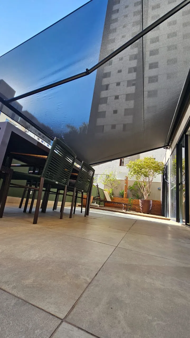 Toldo italiano articulado em tecido escuro sobre terraço
