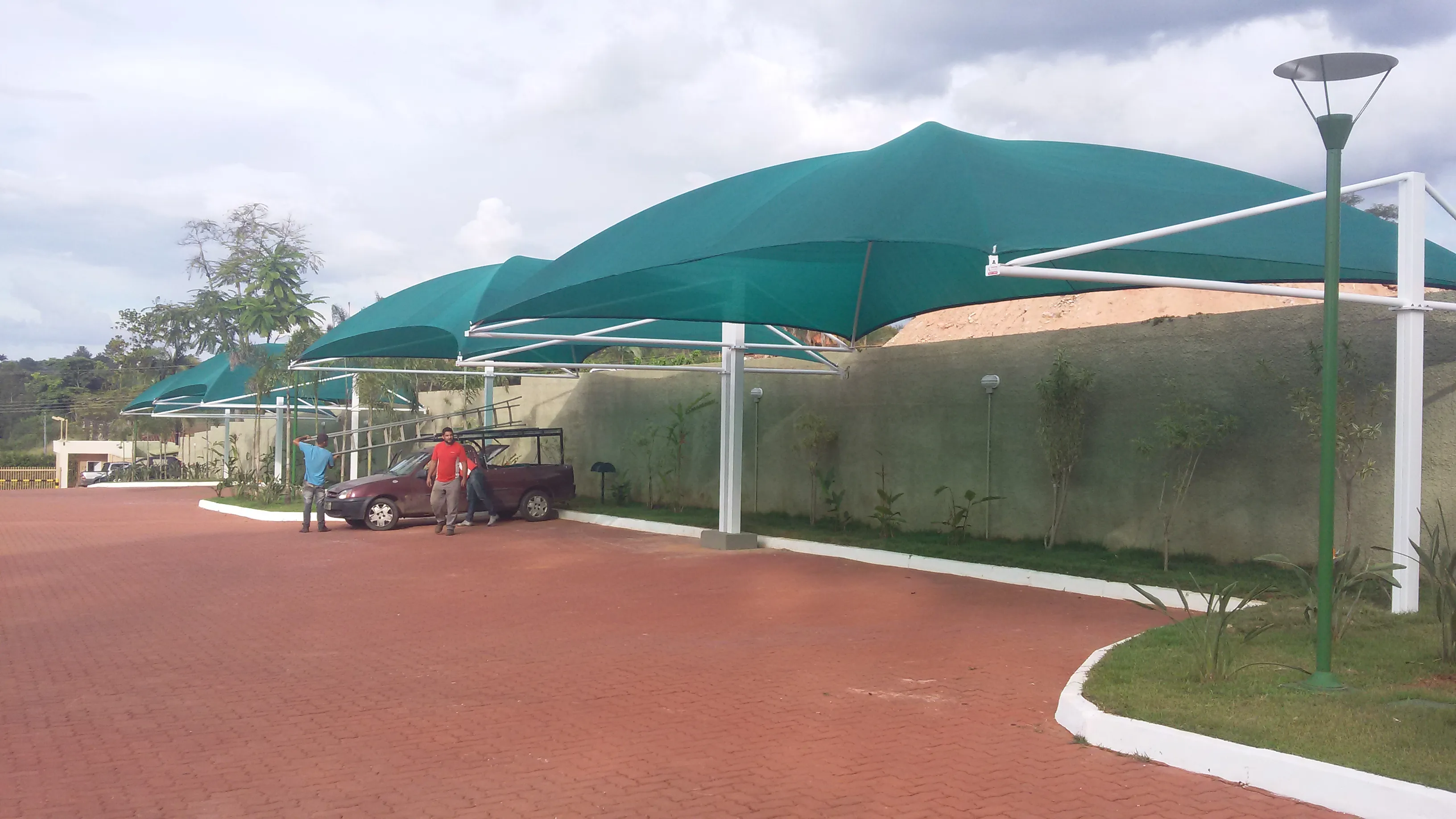 Fileira de sombrites verdes tensionados sobre pátio